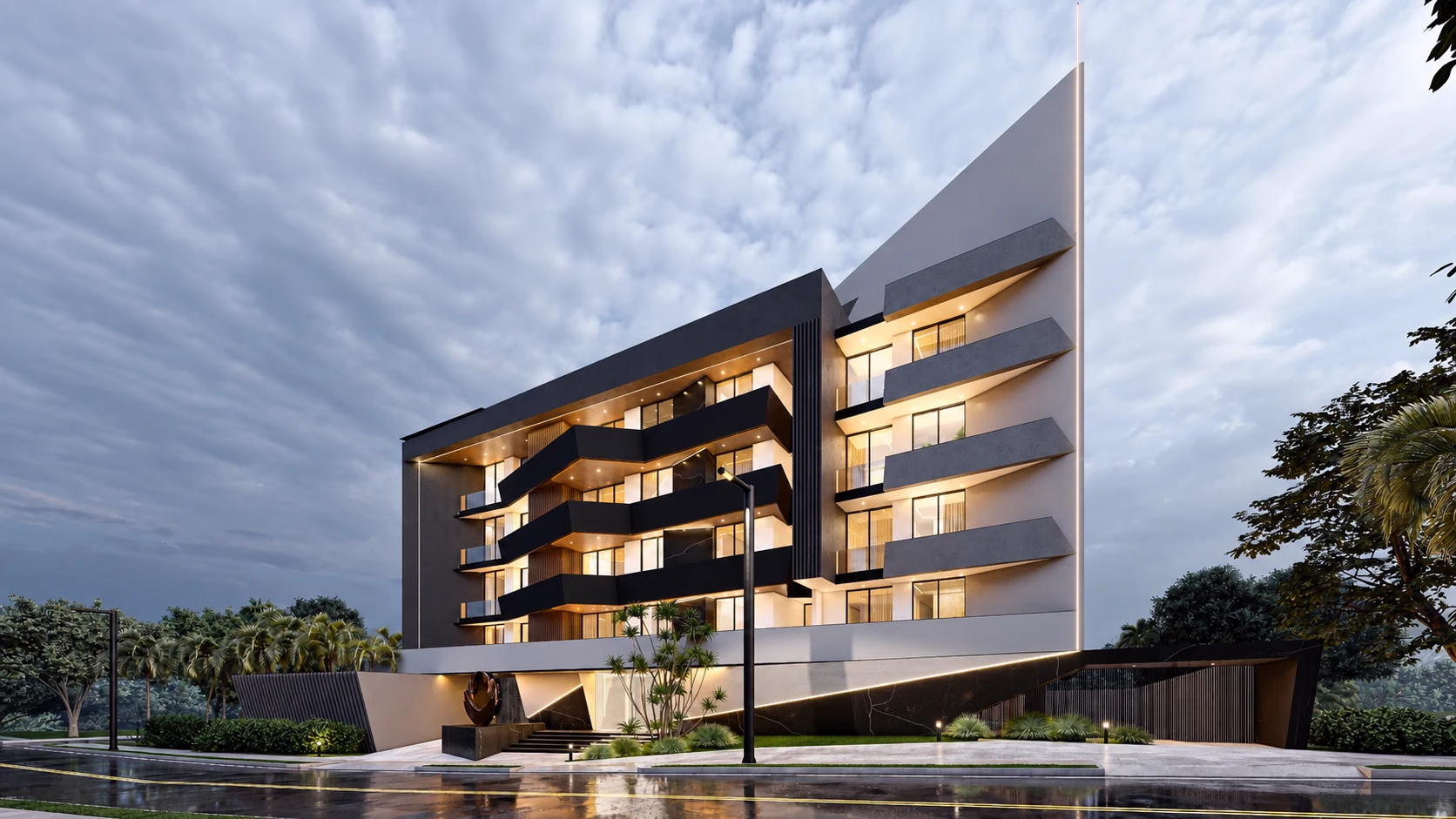 V4 at dusk: the apartment building with its angular black balconies stacked across the elevation, a white fin rising the full height beside them, and the lit entrance reflected in the wet road.